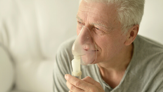 Mann nutzt Inhalationsgerät mit Inhalationslösung zur Inhalation. 